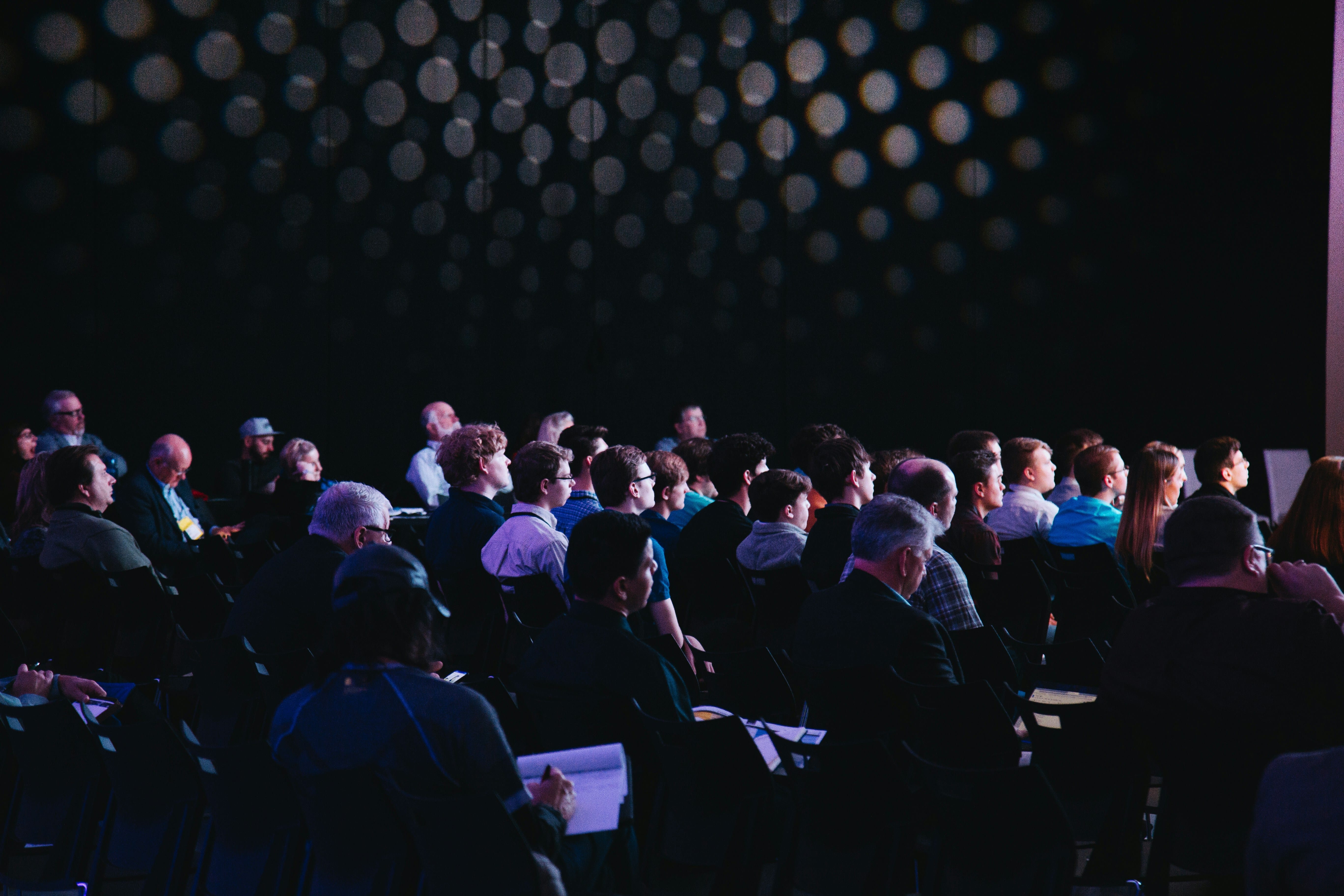 A photo of a conference with lots of people looking at the speaker