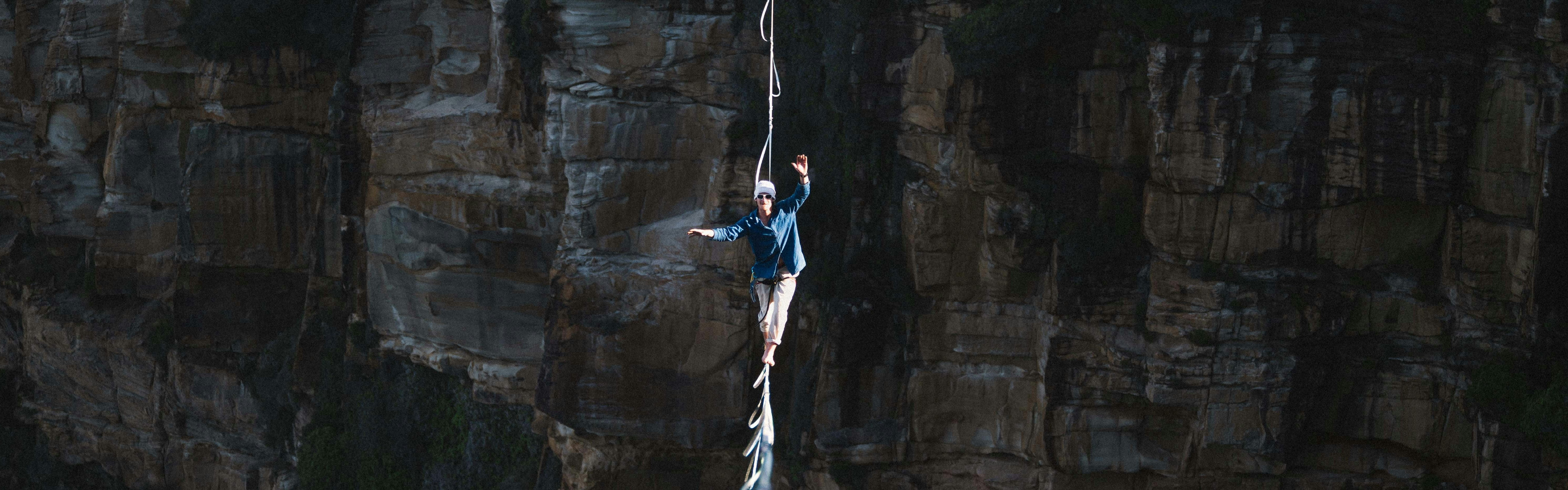 Man walking on a tightrope across a cravass